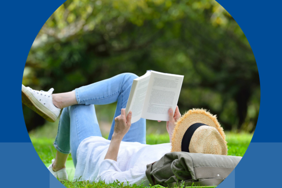 woman reading a book, lying on grass.
