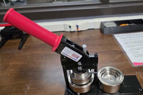 A button maker with a red handle