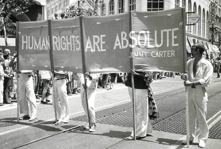 A protest with a large banner.  Humans are Absolute Rights, Jimmy Carter