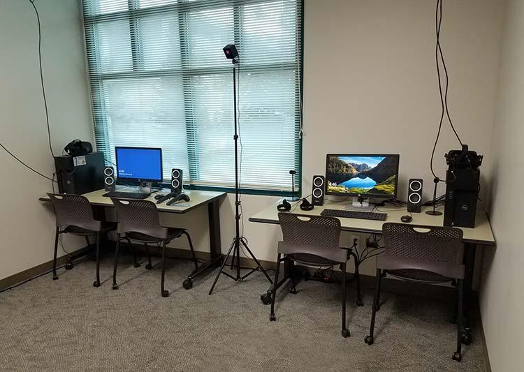 2 desks, each has a computer, and VR equipment.