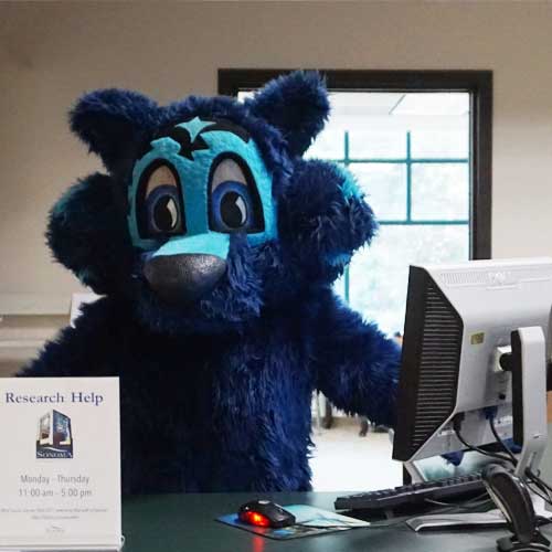 Lobo standing behind a desk, waiting to provide research help.