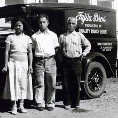 2 men and 2 women stand in front of a truck.