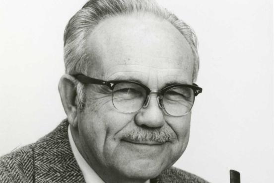 Man wearing glasses and holding a pipe.