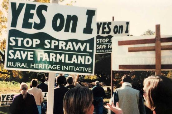 Woman carrying a sign. Yes on I, stop sprawl, save farmland, rural heritage initiative
