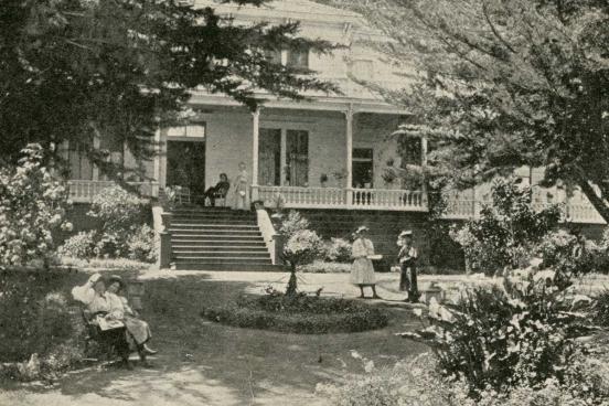 People sitting on a porch on a farmhouse.