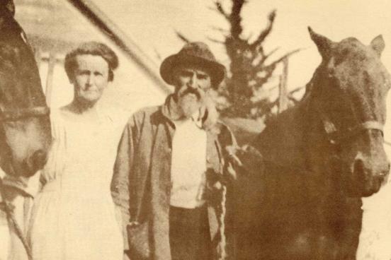 Man and a woman, with a horse on the left and right.