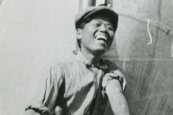 Smiling man standing behind the helm on a ship.