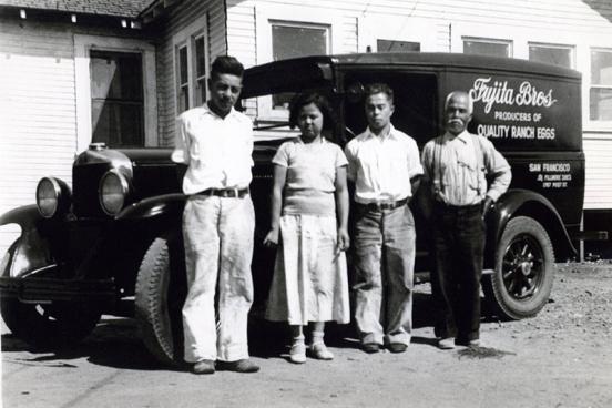 4 people stand in front of a car.