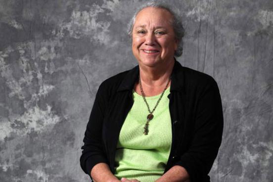 A woman wearing a green shirt and black sweater.