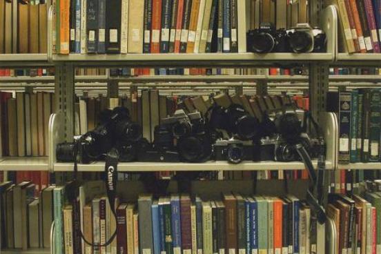 A metal bookshelf filled with film cameras