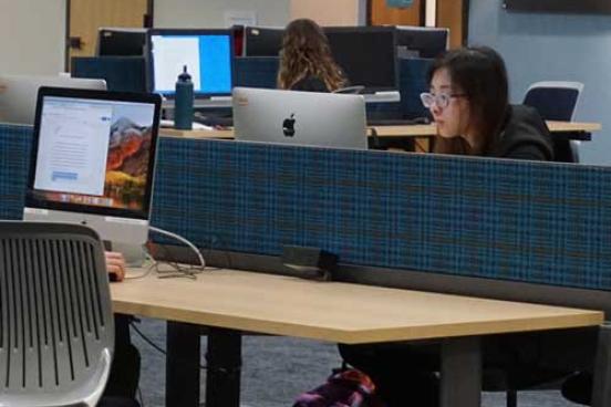 Student at desk, working on a computer 