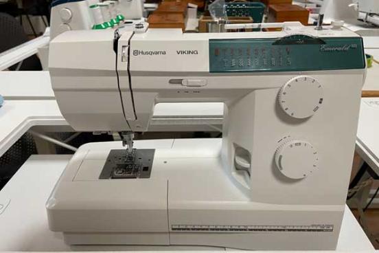 White sewing machine with 2 dials on the right.