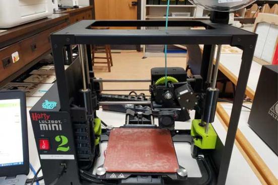 3d printer, the frame is black, Lulzbot Mini text is next to the red power button. 