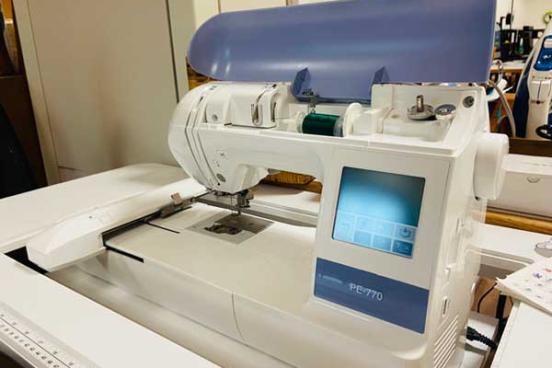 White sewing machine with a display panel on the right.