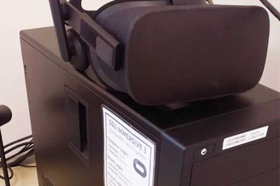 Black VR headset sits on top of a desktop computer.