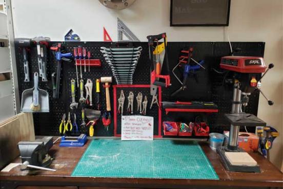 Bench with several tools on the counter and wall.