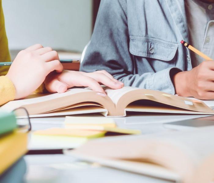 Two people looking over a book, pencils in hands.