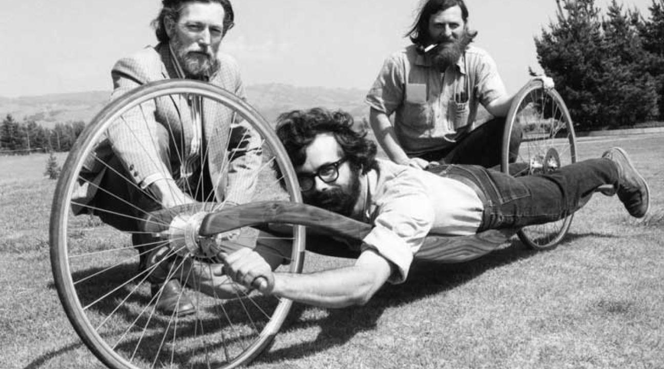 Men demonstrating a soapbox derby vehicle. 
