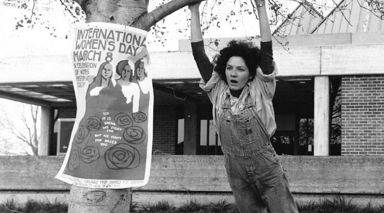 Woman in overalls swinging from a tree.