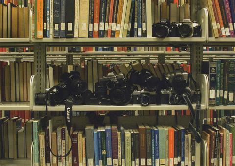 A metal bookshelf filled with film cameras