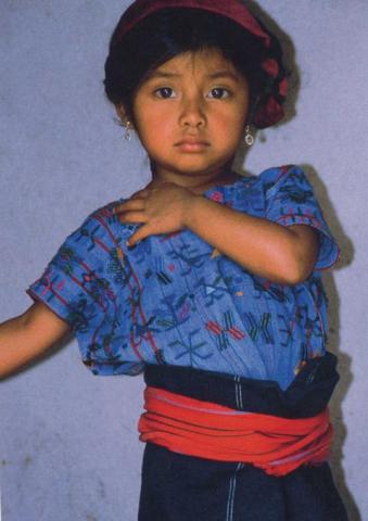 A young girl with a blue shirt and earnings.