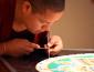 Man slowing added colored sand to the mandala.