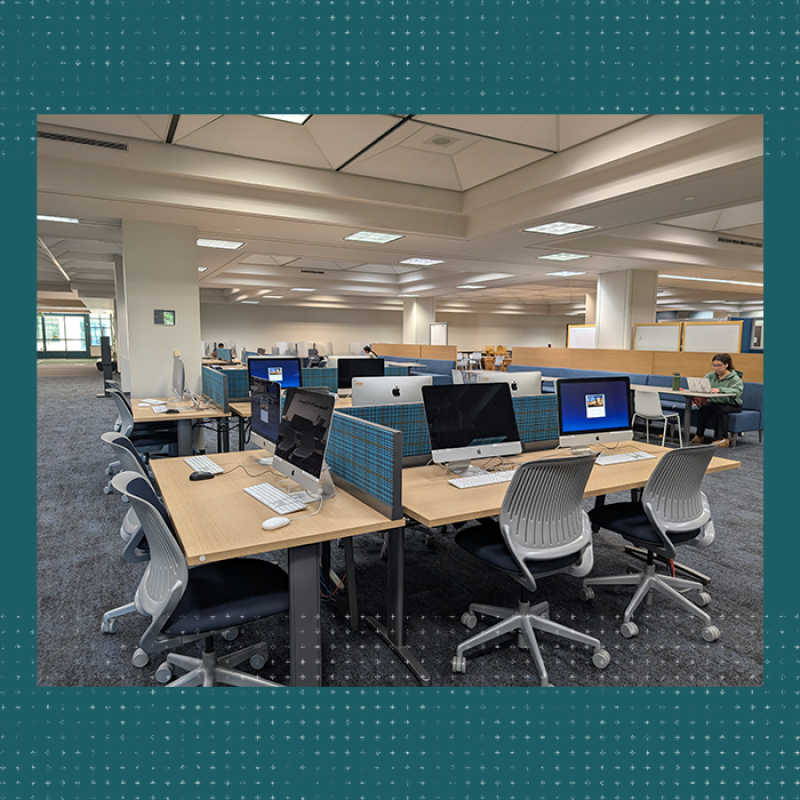 Several tables with computers and chairs in a large room.