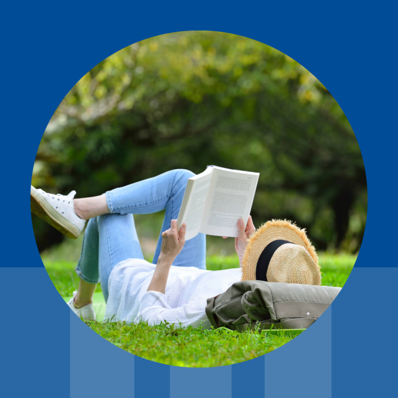 woman reading a book, lying on grass.