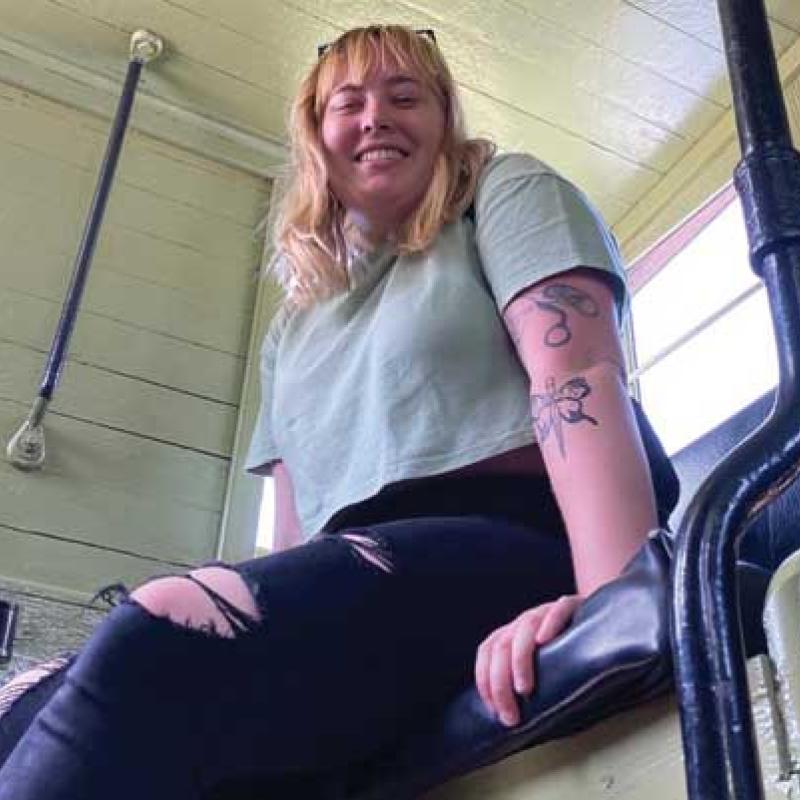 Woman smiling, sitting in a booth. the camera angle is from below.