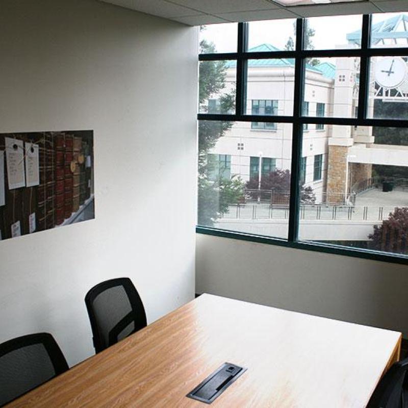 Unoccupied study room with a window, desk and 2 chairs.