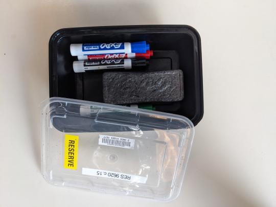 Photo of a box containing white board markers and an eraser