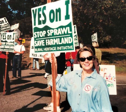 Woman carrying a sign. Yes on I, stop sprawl, save farmland, rural heritage initiative