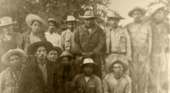 Fourteen men standing in a field.