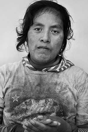 woman wearing a white shirt that has dirt on it.  She is holding her hands.
