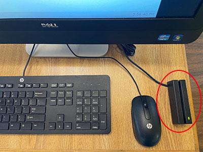 Desk with monitor, mouse, keyboard and a card reader.