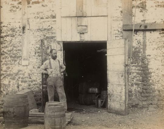 Man in front of an open doorway.  He is wearing overalls.