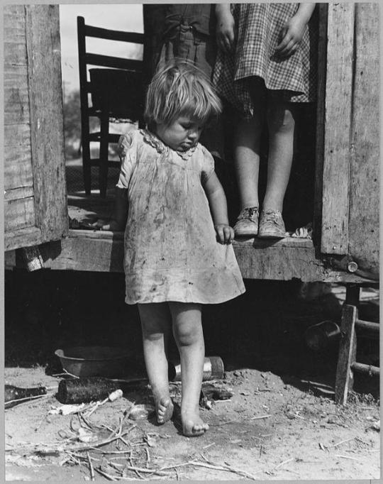 Young girl, barefoot and in a dirty dress.