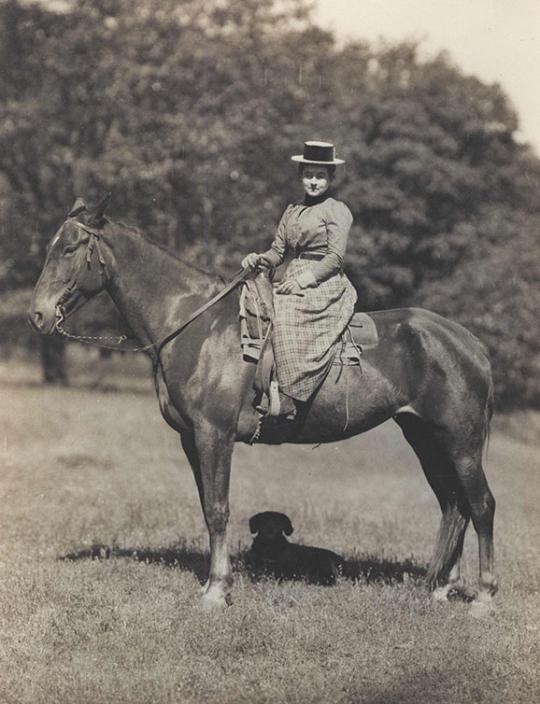 Woman on a horse.  She is dressed in turn of the 20th century clothes.