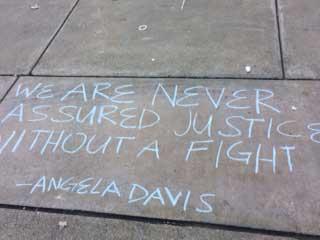 Chalk text of "We are never assured justice without a fight, Angela Davis"