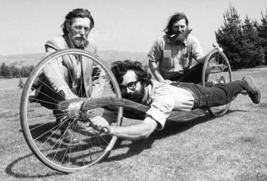 Men demonstrating a soapbox derby vehicle. 