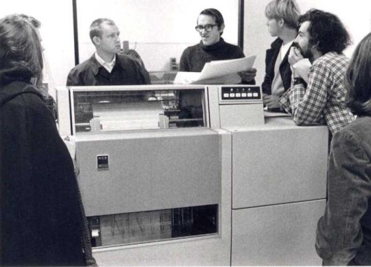 4 people standing behind a large machine.